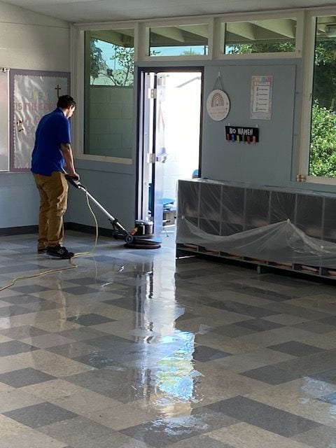 Technician machine-scrubbing a commercial tile floor